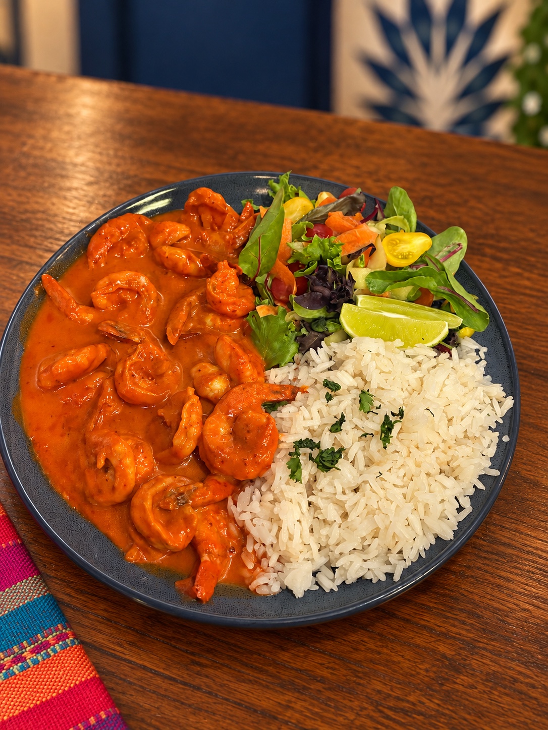 Shrimp in red sauce with rice, salad and lime