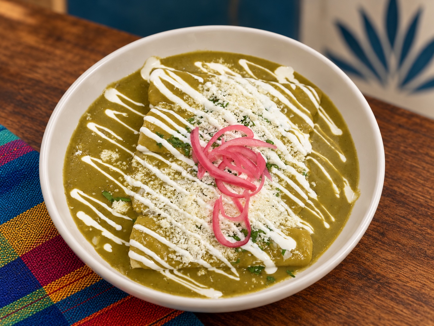Enchiladas topped with house green salsa, crema, cheese, and pickled onions